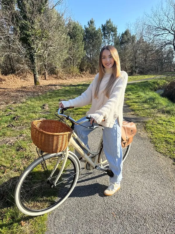 Lilou à vélo avec un panier en osier sur un chemin