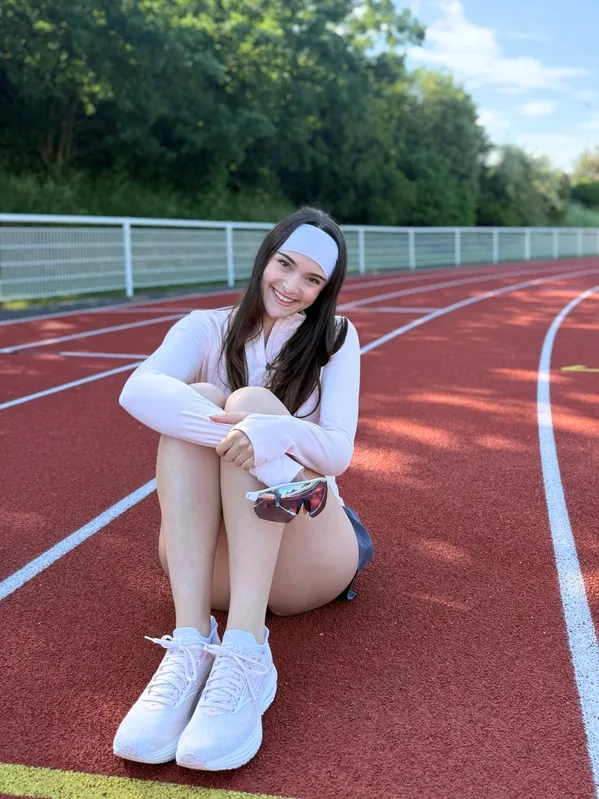 Lilou assise sur une piste d'athlétisme en tenue de sport